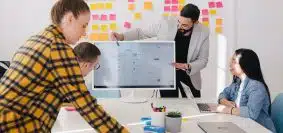 man standing behind flat screen computer monitor