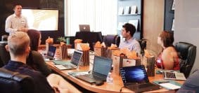 man standing in front of people sitting beside table with laptop computers