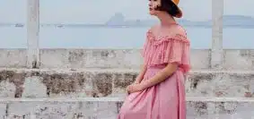 woman wearing pink dress standing next to white wall